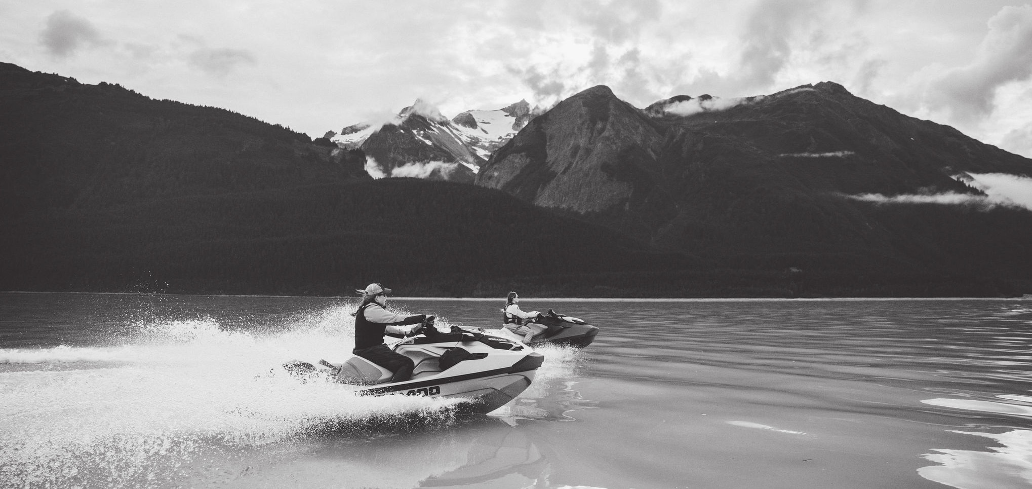 Two Sea-Doo personal watercrafts riding on a body of water Two Sea-Doo personal watercrafts riding on a body of water