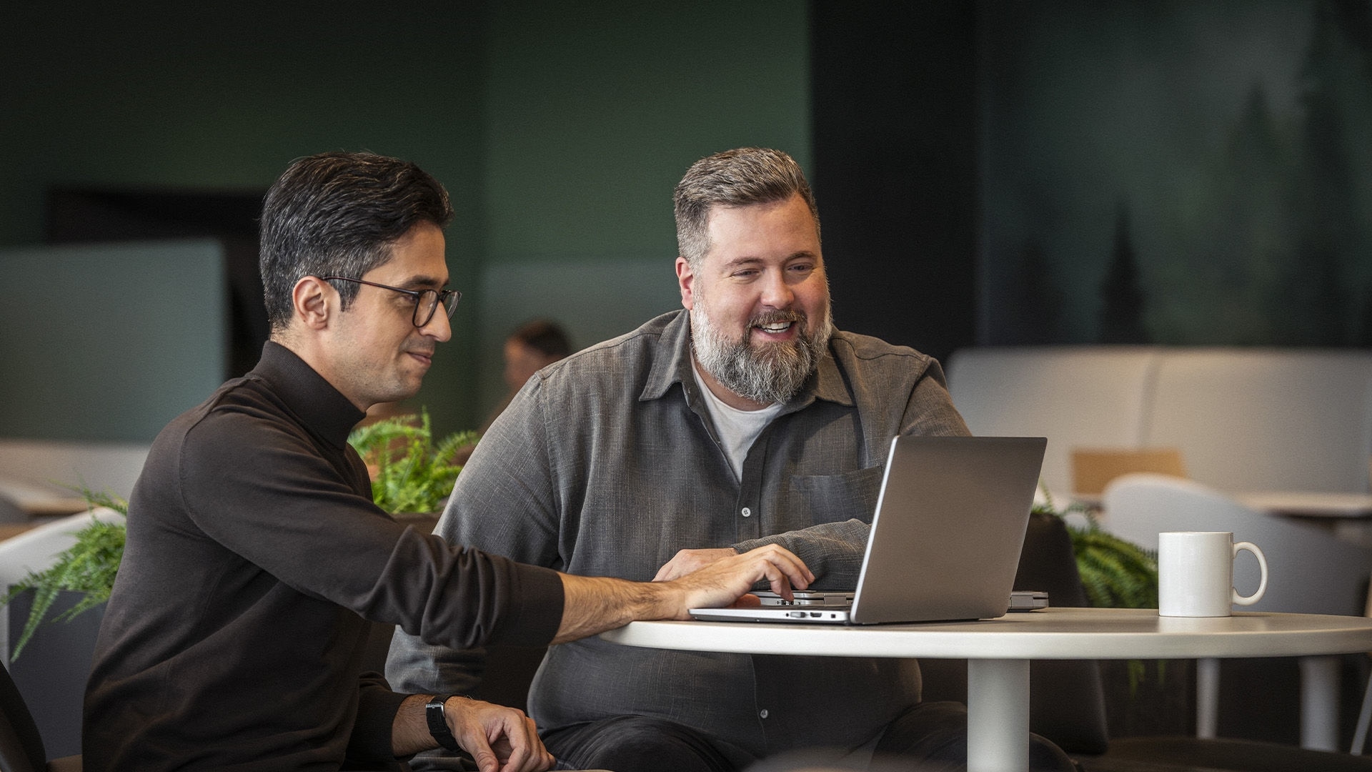 BRP team members collaborating on a laptop within a sophisticated, modern corporate environment.