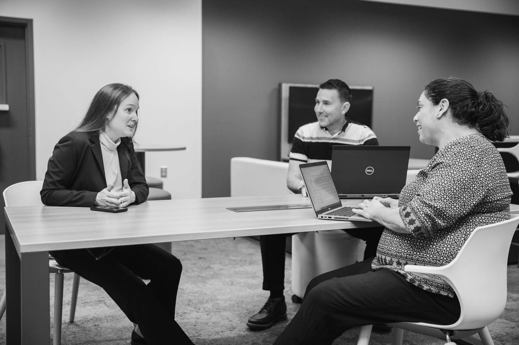 Three BRP employees discussing around a table Three BRP employees discussing around a table