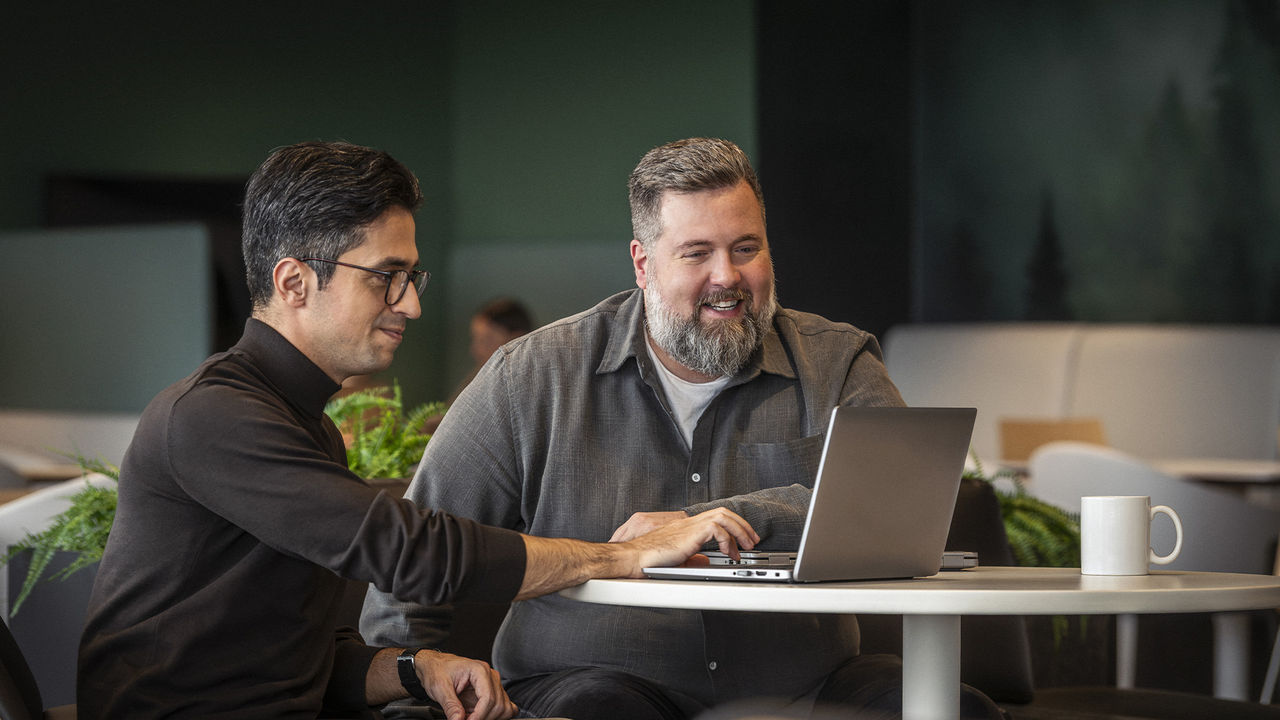 Des membres de l'équipe BRP collaborant sur un ordinateur portable dans un environnement d'entreprise sophistiqué et moderne.
