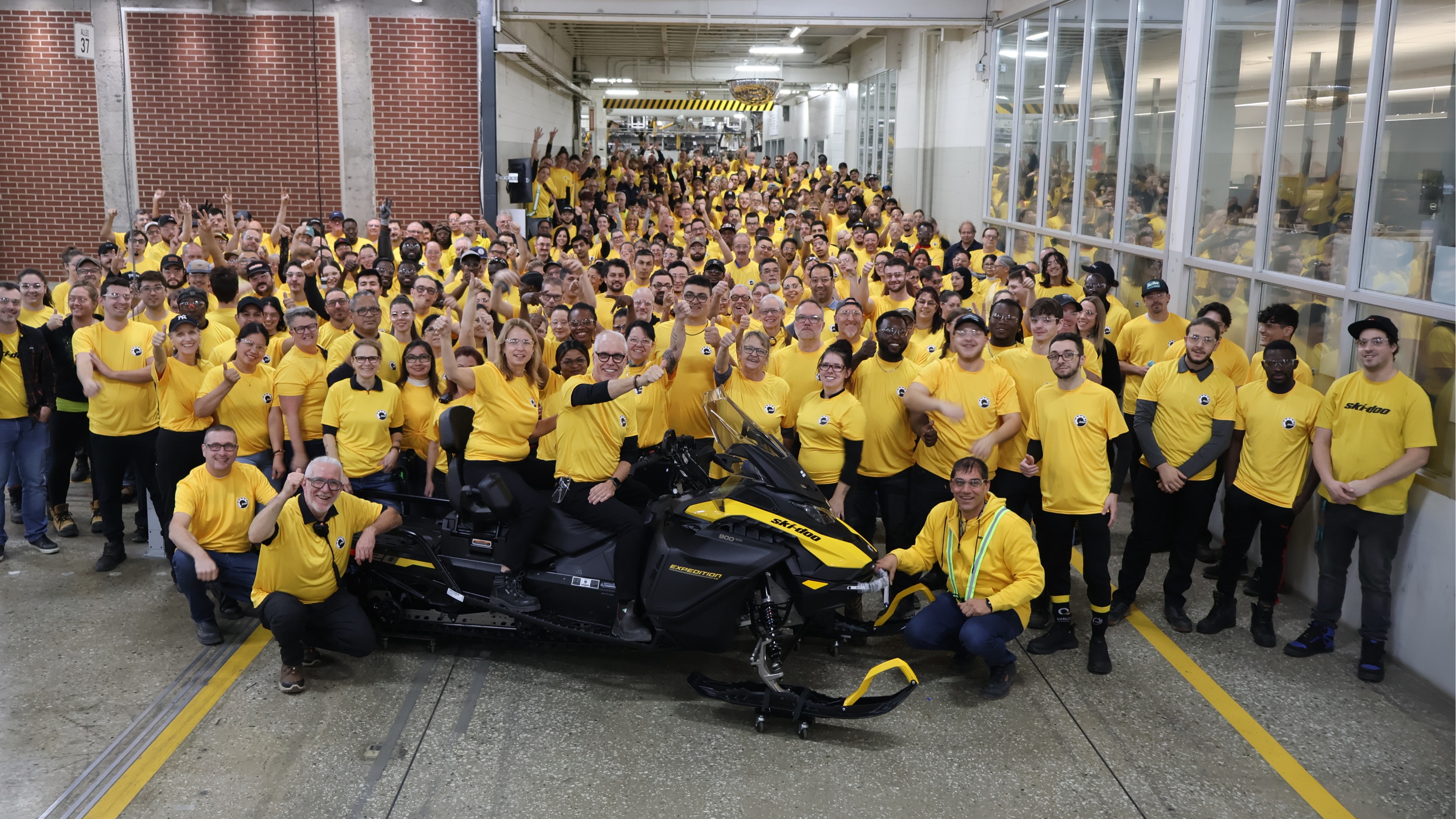 Cabalga la pancarta intimidatoria con gente vestida con camisetas amarillas alrededor de una Ski-Doo.