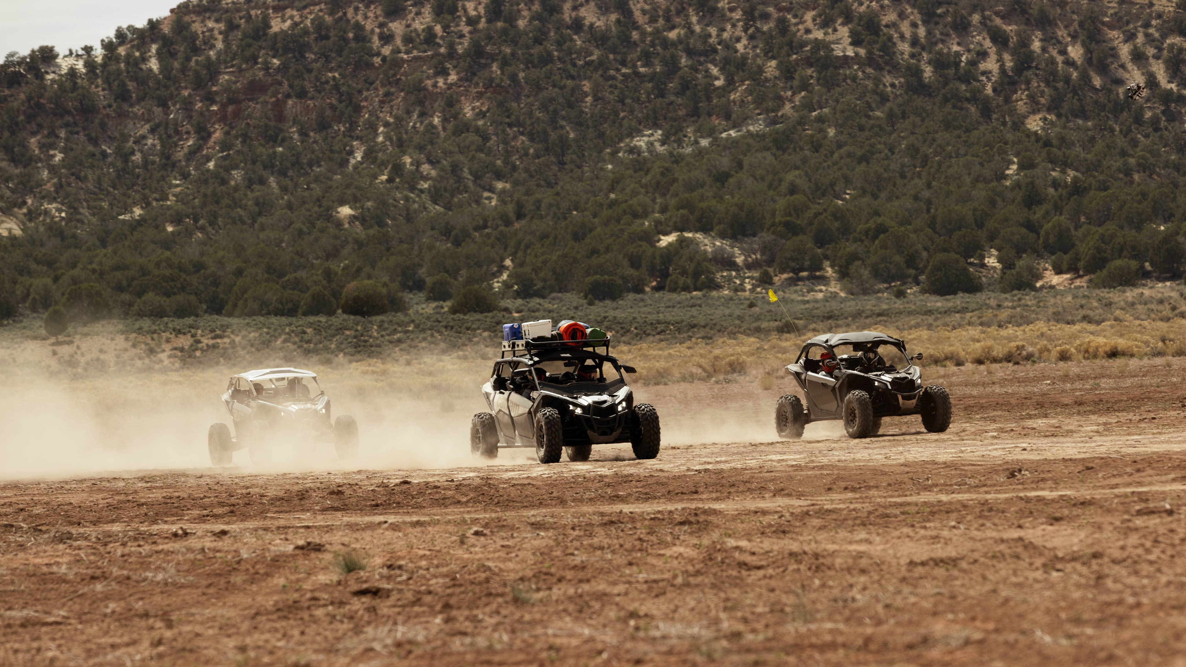 Three Can-Am Side-by-side vehicles riding in the desert