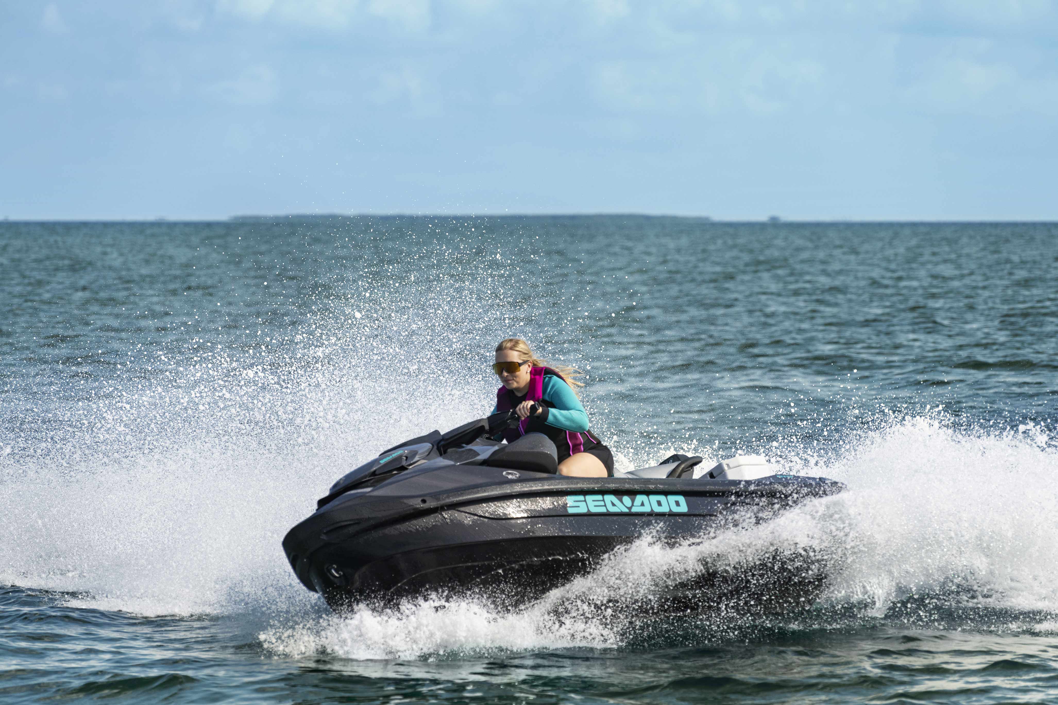 Mujer conduciendo una moto acuática Sea-Doo a gran velocidad