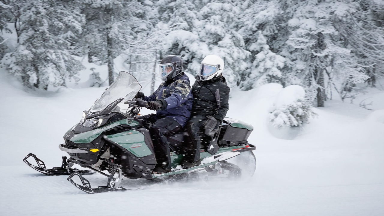 Ski-Doo snowmobile riding in a snowy forest