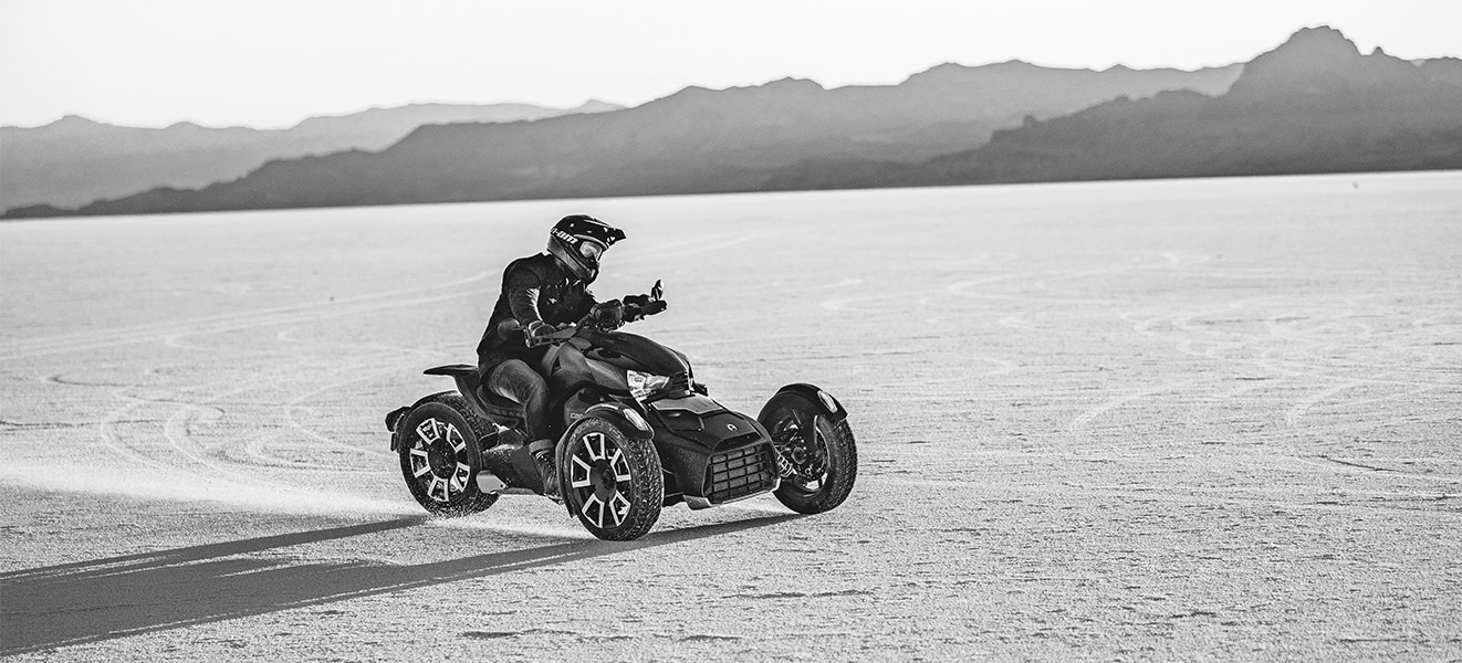 Piloto conduciendo su motocicleta Can-Am de 3 ruedas por un camino de tierra