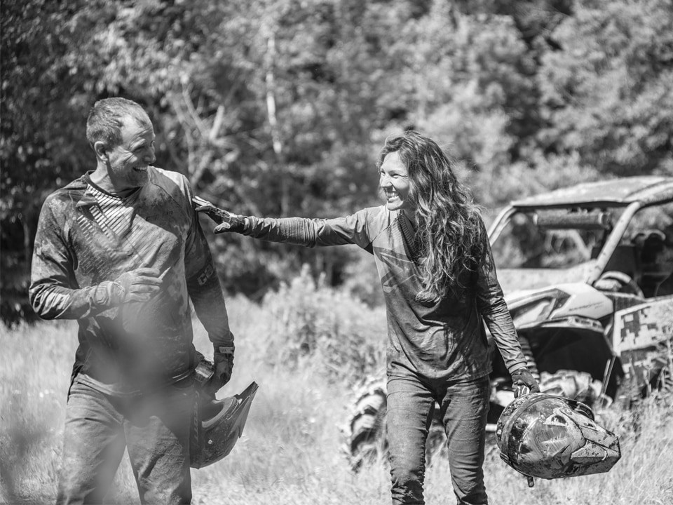 Two riders after a muddy ride with a Can-Am side-by-side vehicle