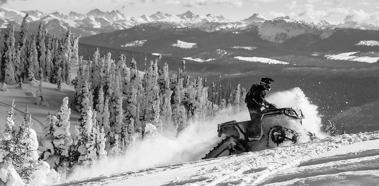 Motociclista escalando una montaña nevada con una moto de nieve Ski-Doo