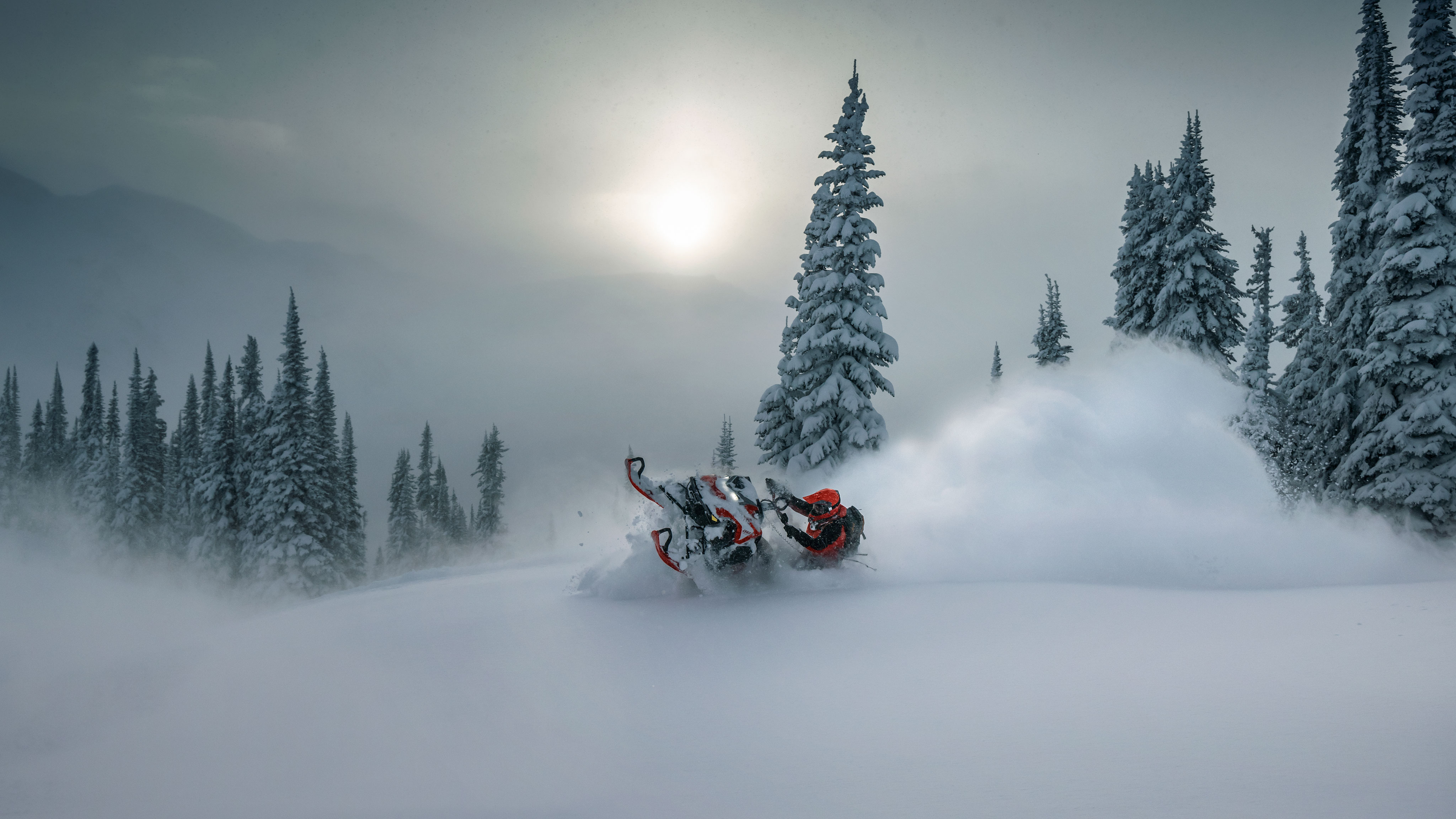 Piloto de moto de nieve realizando un truco en la cima de una montaña nevada